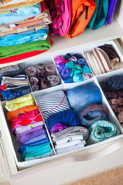 аккуратно сложенная одежда с аксессуарами в комоде
