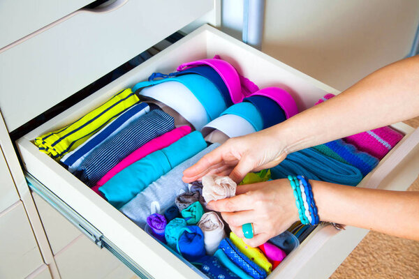 аккуратно сложенная одежда с аксессуарами в комоде
