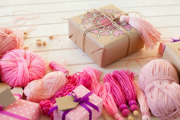 Pembe püsküllü. Beyaz ahşap arka plan. Kadın el sanatları. Yaratıcılık kavramı.