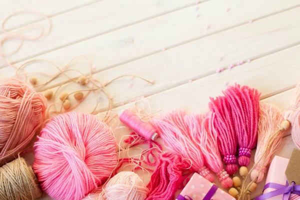 Pembe püsküllü. Beyaz ahşap arka plan. Kadın el sanatları. Yaratıcılık kavramı.
