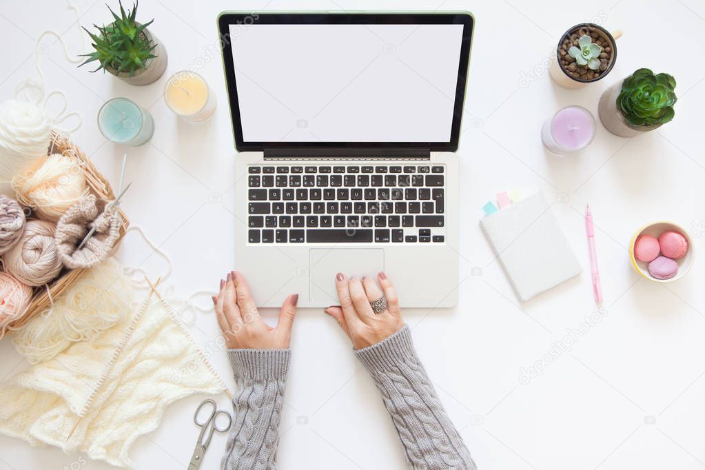 A woman knits, edits an online store on a laptop. Work at home.