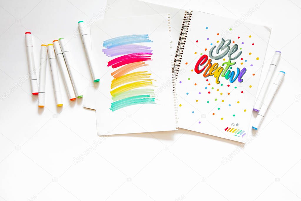graphic design, handwriting, creation concept. tender little hands of female painter inscribing ornamental decorated letters on the white lined paper with Felt-tip pens