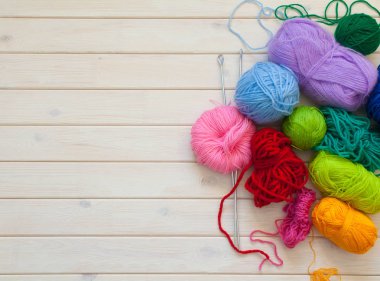 Renkli iplik skeins. Beyaz ahşap arka plan. Örgü iğneleri.