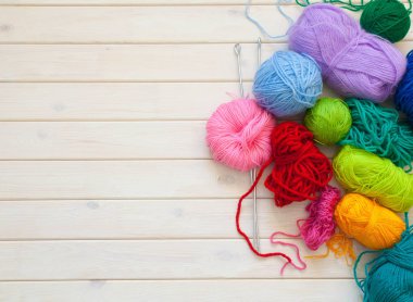 Bir dövme yün bir top şeklinde bir kadınla skein tutar. Arka plan beyaz ahşap.