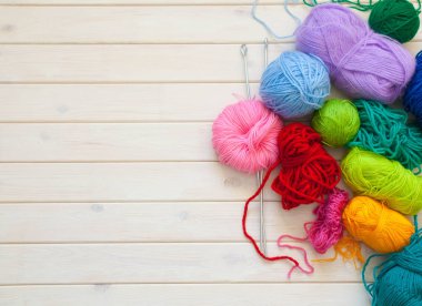 Bir dövme yün bir top şeklinde bir kadınla skein tutar. Arka plan beyaz ahşap.