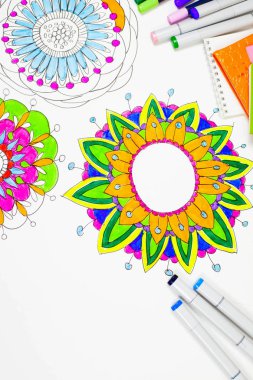 Parlak süs çiçek mandala işaretleri boyalı. Renkli Günlükler ve dizüstü bilgisayarlar. Beyaz arka plan. Yukarıdan görüntülemek.