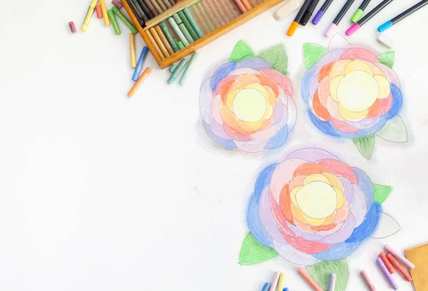 Flowers drawn art with pastels. Pencil, markers and hands of the artist on a white background.