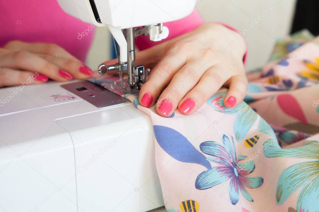 The woman at the sewing machine sews. Cabinet craftswomen and seamstresses. Workshop with tissues.