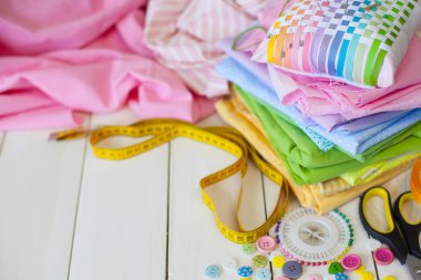 Beyaz bir arka plan üzerinde renkli kumaş Rulolar. Bir tabak üzerinde renkli iplik ile Makaralar. Beyaz arka plan. Yukarıdan görüntüle.