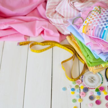 Beyaz bir arka plan üzerinde renkli kumaş Rulolar. Bir tabak üzerinde renkli iplik ile Makaralar. Beyaz arka plan. Yukarıdan görüntüle.