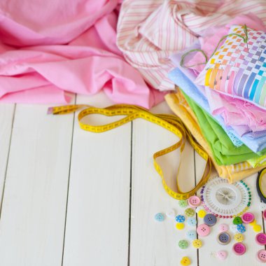 Beyaz bir arka plan üzerinde renkli kumaş Rulolar. Bir tabak üzerinde renkli iplik ile Makaralar. Beyaz arka plan. Yukarıdan görüntüle.