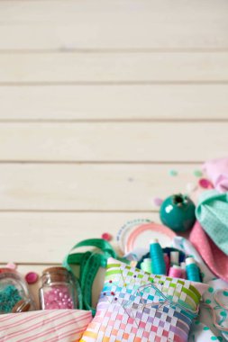 Dikiş aksesuarları beyaz bir arka plan üzerinde yalan. Ölçüm bandı, iplik, kumaş ve Dikiş iğneler. Kumaş pembe, nane ve turkuaz.