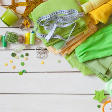 Dikiş için malzemeler. Renkli kumaş, iplik ve beyaz bir arka plan üzerinde düğmeleri. Renkli iğne iğne Yataklı.