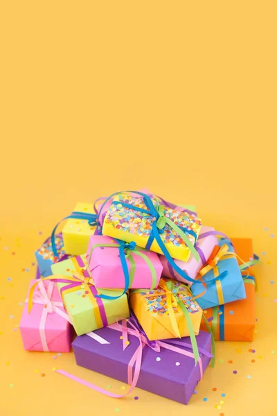Colored gift boxes with colorful ribbons. Yellow background. Gifts for Christmas or a birthday.