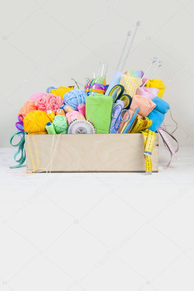 basket with accessories for needlework on wooden table