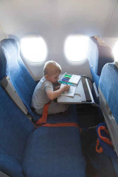 A boy drawing in an airplane. Child in flight.