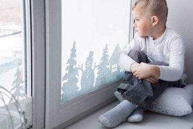 Çocuk renkli kalem ve marker ile bir Noel ağacı çizer