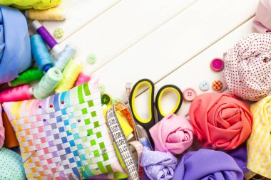 Dikiş aksesuarları beyaz bir arka plan üzerinde yalan. Ölçüm bandı, iplik, kumaş, İğne mili ve iğneler dikiş için.