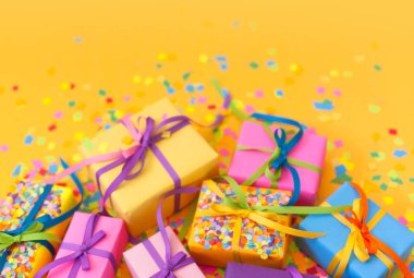 Renkli hediye kutuları renkli şeritler. Sarı arka plan. Noel veya doğum günü için hediyeler.