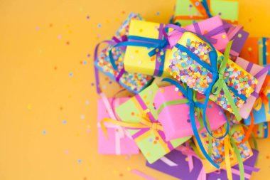 Renkli hediye kutuları renkli şeritler. Sarı arka plan. Noel veya doğum günü için hediyeler.