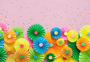 Renkli parlak kağıt rozet. Dekorasyon için bir parti. Pembe bir arka plan. 