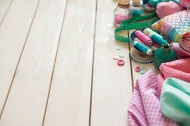 Dikiş aksesuarları beyaz bir arka plan üzerinde yalan. Ölçüm bandı, iplik, kumaş ve Dikiş iğneler. Kumaş pembe, nane ve turkuaz.