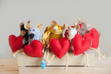 Örme fare oyuncakları kırmızı kalpler tutun.