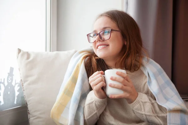 女孩坐在窗边，手里拿着一个白色的杯子。Bla — 图库照片