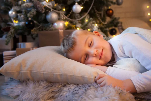 少年は白い帽子でクリスマスツリーの近くで眠っていて、鞭 — ストック写真