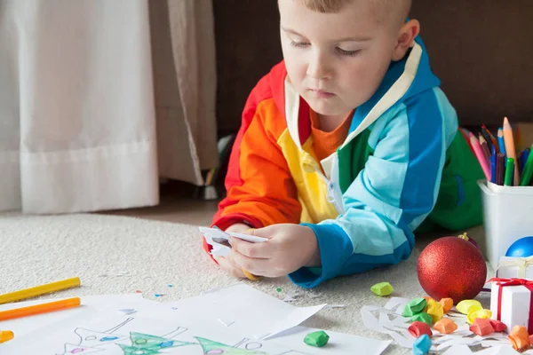 Un ragazzo in abiti colorati scolpisce i fiocchi di neve di Capodanno . — Foto Stock