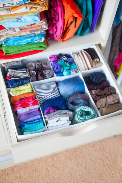 аккуратно сложенная одежда с аксессуарами в комоде
