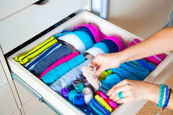 аккуратно сложенная одежда с аксессуарами в комоде
