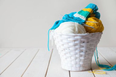 Yün iplik bobinleri ve tangles beyaz sepet içinde. Beyaz ahşap tablo.