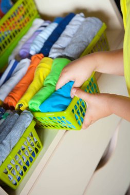 Çocuğun elbiselerini koyar. Çocuk T-shirt dolaptan çeker.