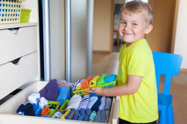 Çocuğun elbiselerini koyar. Çocuk T-shirt dolaptan çeker.