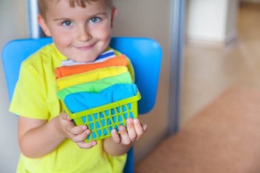 Çocuk eşyaları duruyor. Çocuk T-shirt bir drawe koyar.