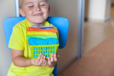 Çocuk eşyaları duruyor. Çocuk T-shirt bir drawe koyar.