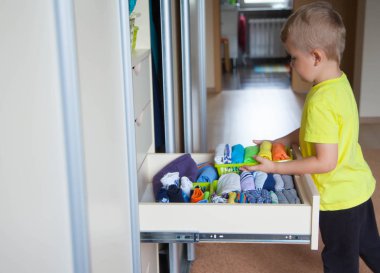 Çocuğun elbiselerini koyar. Çocuk T-shirt dışarı çeker 