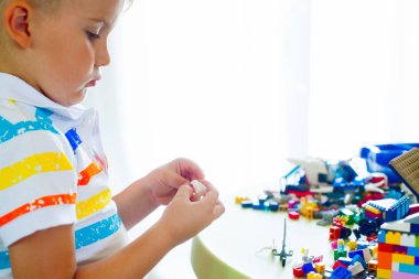 Küçük sarışın çocuk çocuk renkli plastik blok kapalı birçok ile oyun. Lego blokları sıralanır. Lego klasik depolama.