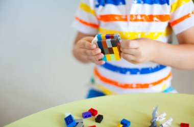 Küçük sarışın çocuk çocuk renkli plastik blok kapalı birçok ile oyun. Lego blokları sıralanır. Lego klasik depolama.