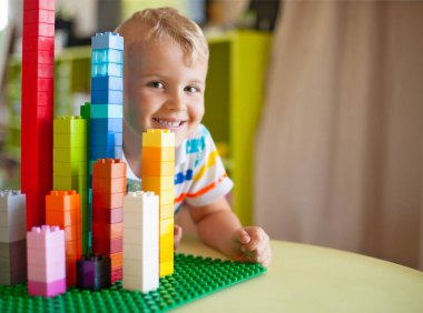 Küçük sarışın çocuk çocuk renkli plastik blok kapalı birçok ile oyun. Lego Duplo
