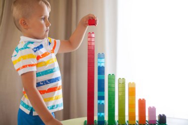 Küçük sarışın çocuk çocuk renkli plastik blok kapalı birçok ile oyun. Lego Duplo