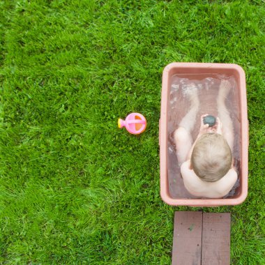 Yeşil çimenlerin üzerinde banyoda küçük çocuk yıkar. 4-5 yıl açık havada oynayan eski çocuk. Alma banyo. Çocukluk. Happiiness.