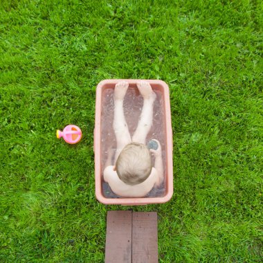 Yeşil çimenlerin üzerinde banyoda küçük çocuk yıkar. 4-5 / çocuk