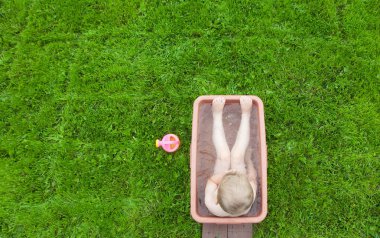 Yeşil çimenlerin üzerinde banyoda küçük çocuk yıkar. 4-5 / çocuk