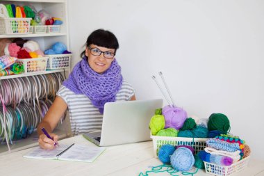 Atölyeden genç bir kadın. Örme ve kroket. Bir sepet içinde iplik saç. Beyaz arka plan.