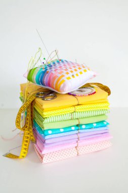 Dikiş için malzemeler. Renkli kumaş, iplik ve beyaz bir arka plan üzerinde düğmeleri. Renkli iğne iğne Yataklı.