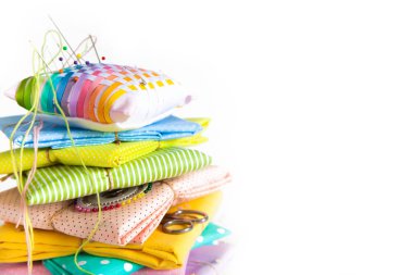 Dikiş için malzemeler. Renkli kumaş, iplik ve beyaz bir arka plan üzerinde düğmeleri. Renkli iğne iğne Yataklı.