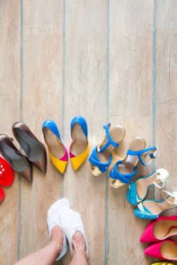 Bir sürü yerde renkli kadın ayakkabısı. Bir kadın ayakkabıları seçer.