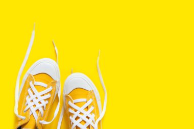 Sarı bir arka plan üzerinde kısa düşük parlak spor ayakkabı.